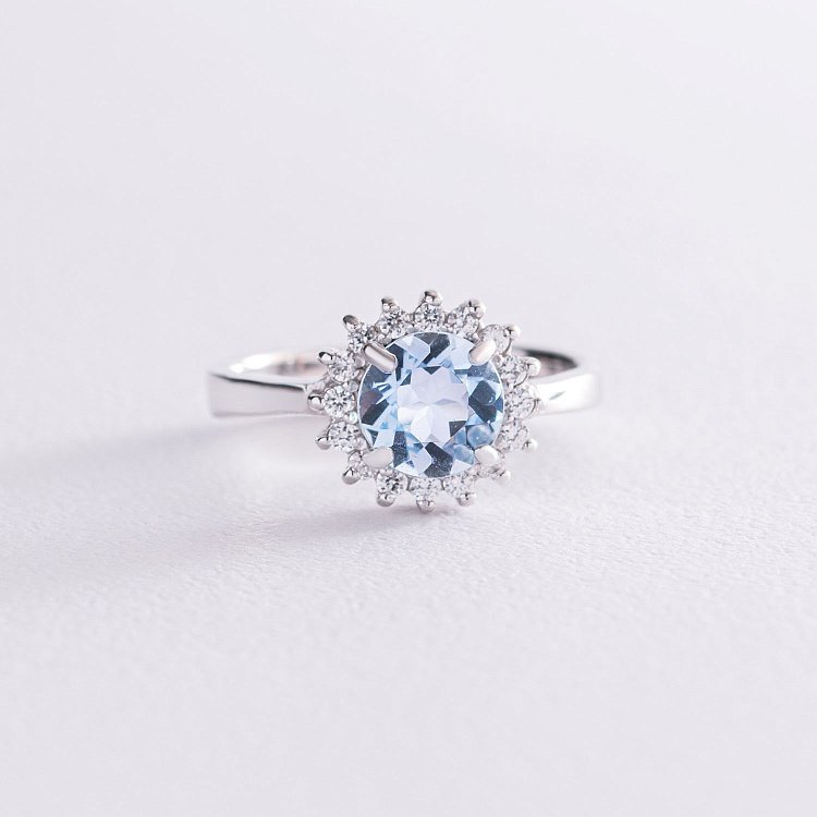 Срібна каблучка з блакитним топазом і фіанітами 111056 Срібна каблучка з блакитним топазом і фіанітами 111056 від ювелірного магазину Онікс